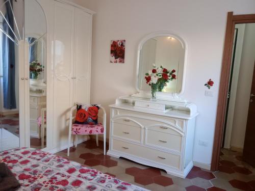 a white dresser with a mirror and a vase of flowers at Appartamento vacanze Le rose in Bosa