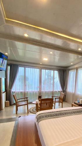 a bedroom with a bed and a large window at De Pointé Resort & Resto in Campaka
