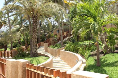 a garden with palm trees and a wooden fence at Hotel Jardin Savana Dakar in Dakar