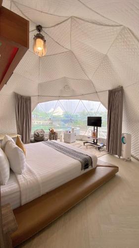 a large bed in a room with a view at De Pointé Resort & Resto in Campaka