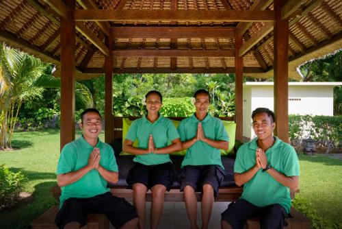 four men in green shirts sitting on a bench praying at Exclusive private villa Beten Bukit - mountain view & private swimming pool in Pemuteran