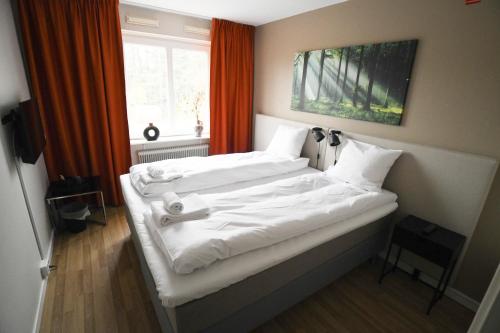 a bedroom with two beds with white sheets and a window at Lycksele Inn in Lycksele