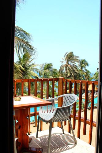 a table and a chair on a balcony with palm trees at Hotel Jardin Savana Dakar in Dakar