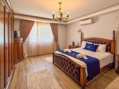 a bedroom with a bed with blue sheets and a chandelier at Villa Limon in Kuşadası
