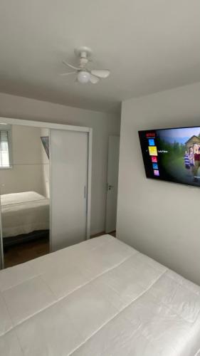 Un dormitorio con una cama y un televisor de pantalla plana en la pared. en Apartamento - Zona Sul SP, en São Paulo