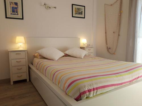 1 cama con manta a rayas y 2 almohadas en Apartamento en Salou-Vistas al Mar, en Salou