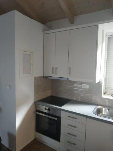 a kitchen with white cabinets and a black oven at Sofias house at Agkona Kefalonia in Angón