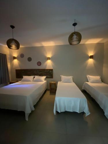 a bedroom with two beds and two lights on the wall at Pousada Cigarras da Serra in Serra do Cipo