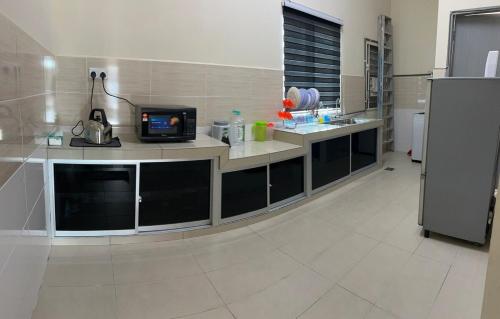 una cocina con encimera y TV. en RB Homestay Modern Comfort, en Hutan Melintang