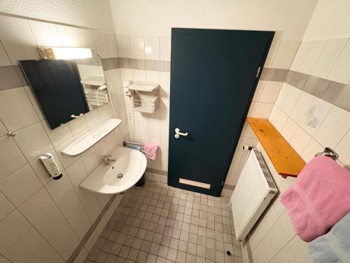 a bathroom with a sink and a blue door at Landhaus Ostseeblick in Kronsgaard