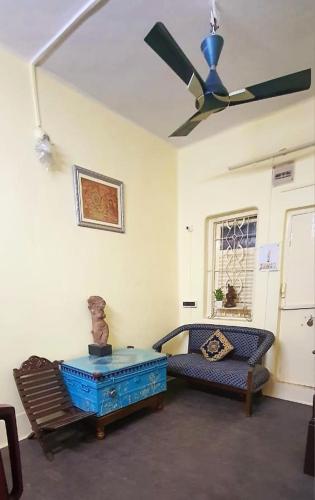 a living room with a ceiling fan and a couch at Mandira's Home in Kolkata