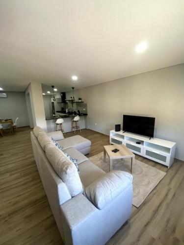 a living room with a white couch and a tv at Casa da Boucinha in Celorico de Basto