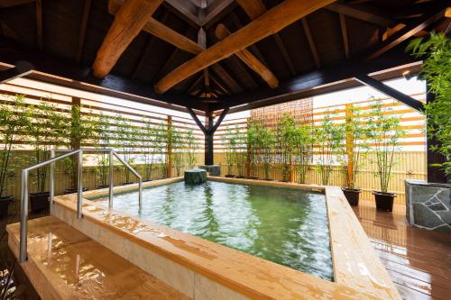 an indoor swimming pool in a building with trees at BeppuOnsen Hotel Sansenkaku in Beppu