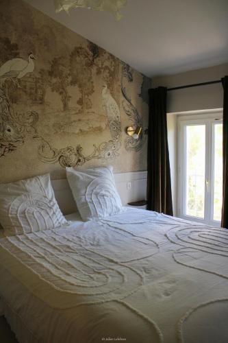 une chambre avec un grand lit blanc avec une fenêtre dans l'établissement L escale Antique, à Nîmes