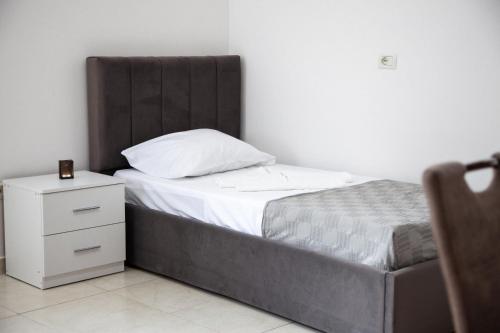 a bed with a wooden headboard and a white night stand at VIJA Holiday Rooms Shengjin in Shëngjin