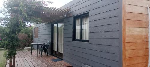 a deck with a table and chairs on a house at PUNTA NEGRA DISFRUTABLE TODO EL AÑO! in Punta Colorada