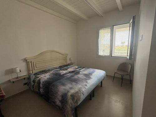 Un dormitorio con una cama y una silla y una ventana. en Casa Dei Gelsi, en Pozzallo