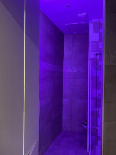 La salle de bains est pourvue d'une douche avec un éclairage violet. dans l'établissement Plein coeur, à Montpellier