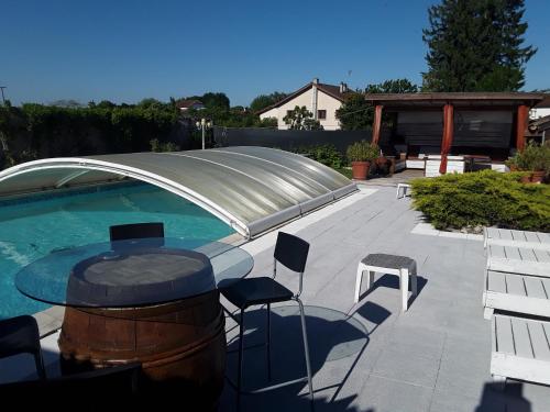 un patio avec une table et des chaises à côté d'une piscine dans l'établissement Le lion d'or, à Marlieux