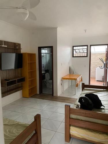 a living room with a bed and a flat screen tv at Apartment in Prainha Caraguá in Caraguatatuba