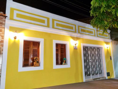 a yellow house with two windows with stuffed animals in it at Casa Seu Quinca - Portalegre, RN Brasil in Portalegre