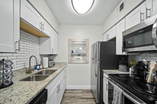a kitchen with white cabinets and a stainless steel refrigerator at Spacious and Stylish Apartment right by AT&T Stadium! in Arlington