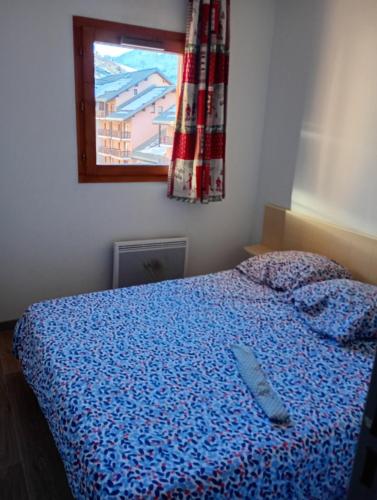une chambre avec un lit avec une couette bleue et une fenêtre dans l'établissement appartement valmeinier 1800, à Valmeinier