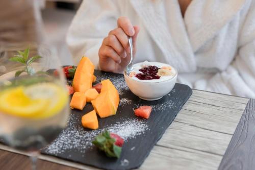 a person eating a plate of food with a bowl of fruit at Hotel Delle Terme Santa Agnese in Bagno di Romagna