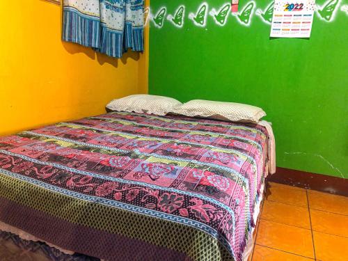 a bed in a room with a green wall at Hotel Henderson in San Pedro La Laguna