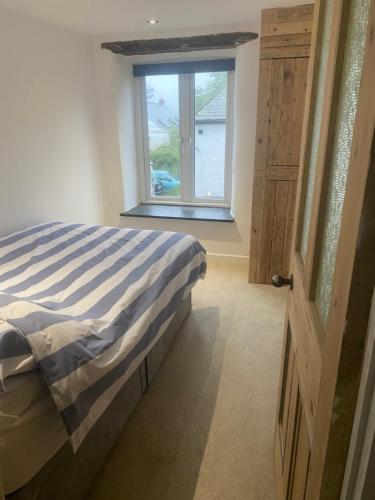 a bedroom with a bed and a window at Hideaway Cottage in Camelford