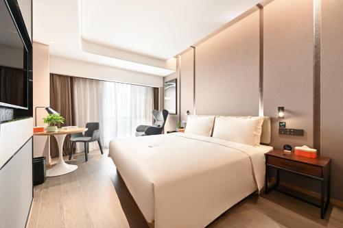 a hotel room with a large white bed and a desk at Atour Hotel Beijing Lishuiqiao in Changping