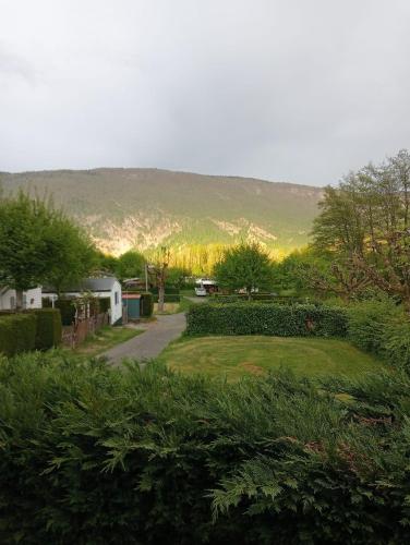une cour herbeuse avec une montagne en arrière-plan dans l'établissement mobilhome Aiguebelette Aix les bains, à La Combe