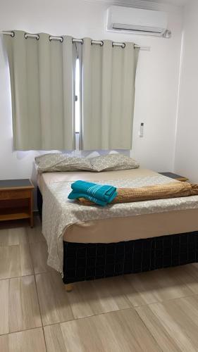 a bedroom with a bed with blue towels on it at Aconchego Jardim Ipê proximo ao Paraguai in Foz do Iguaçu