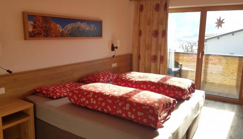three red pillows sitting on a bench in a room at Hotel Alpenpanorama in Söll