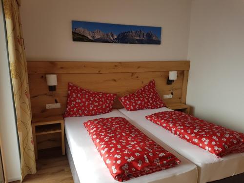 two beds in a room with red pillows at Hotel Alpenpanorama in Söll