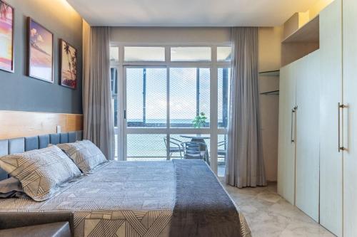 a bedroom with a bed and a large window at Flat Beira Mar in Recife