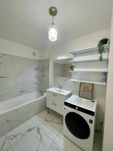 une salle de bain blanche avec un lavabo et une baignoire dans l'établissement Coté Paname large 2 bedroom apartment with parking space, à Clichy