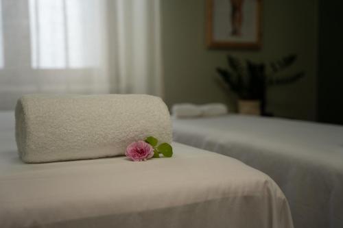 a pink flower sitting on top of a white bed at Hotel Florence in Manerba del Garda