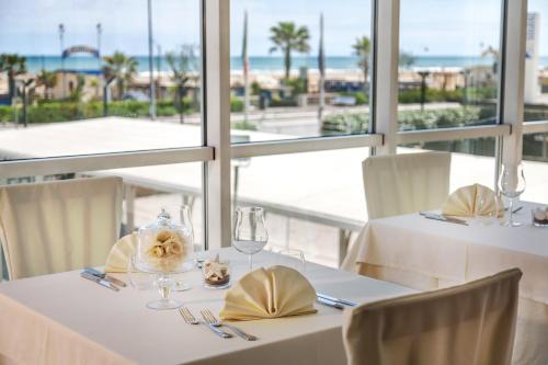 una sala da pranzo con due tavoli e vista sull'oceano di Hotel Kursaal a Rimini