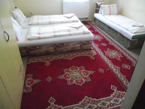 two beds in a room with a red rug at Penzión Slávia in Poprad