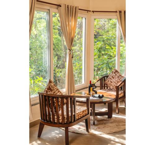 a room with a table and chairs and windows at Jungle Ghar in Pachmarhī