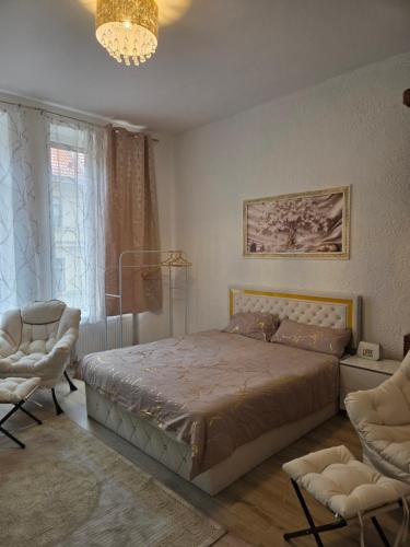 a bedroom with a bed and two chairs and a chandelier at Apartments Angels o k b in Altenburg