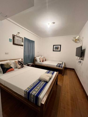 a bedroom with two beds and a tv on the wall at Casa Montemar Heights in Coron