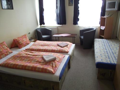two beds in a room with chairs and windows at Penzión Slávia in Poprad