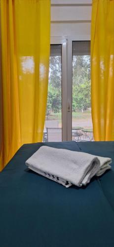 a white towel sitting on a bed with yellow curtains at Montebello Inn apartments in Ulcinj