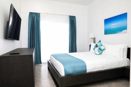 a bedroom with a bed and a tv and a window at Ocean Breeze Resort in NCA