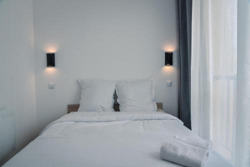 - un lit avec des draps et des oreillers blancs à côté d'une fenêtre dans l'établissement Appartement cosy proche océan, à Seignosse