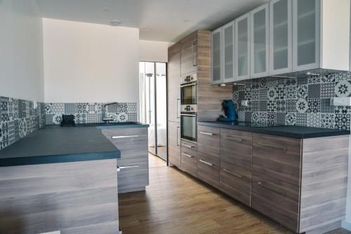 une cuisine avec des placards en bois et des comptoirs noirs dans l'établissement Appartement cosy proche océan, à Seignosse