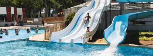 un groupe de personnes jouant sur un toboggan aquatique dans une piscine dans l'établissement MOBIL-HOME HAUT DE GAMME - PROCHE MER - 3 Chambres - Dressing, à Piriac-sur-Mer