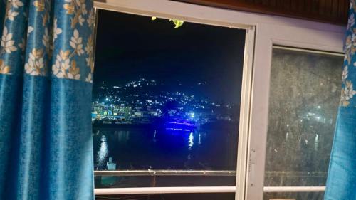 a window with a view of a river at night at Anushree Lake View Home Stay Uttarkashi in Uttarkāshi